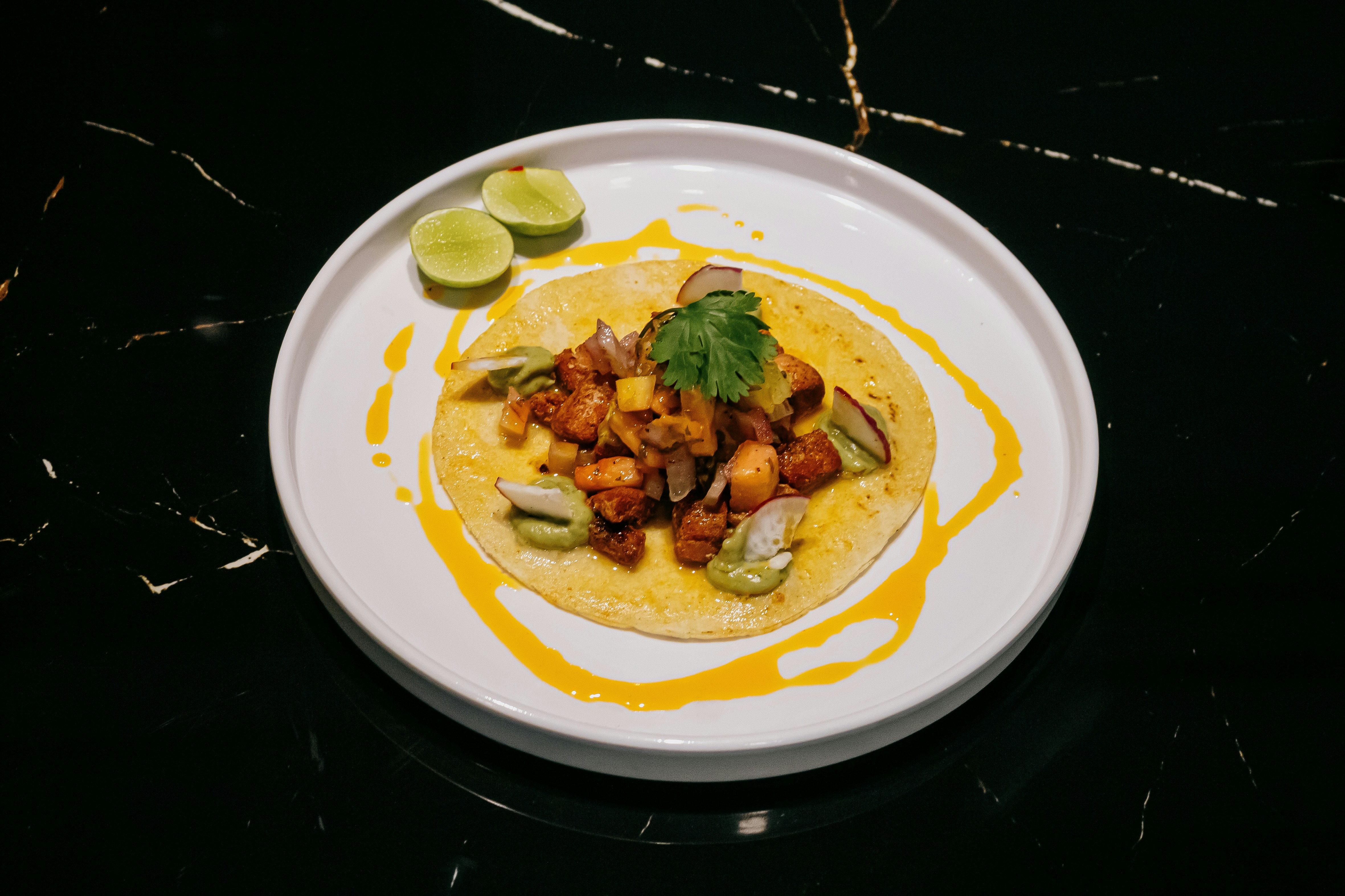 A taco garnished with coriander and lime halves