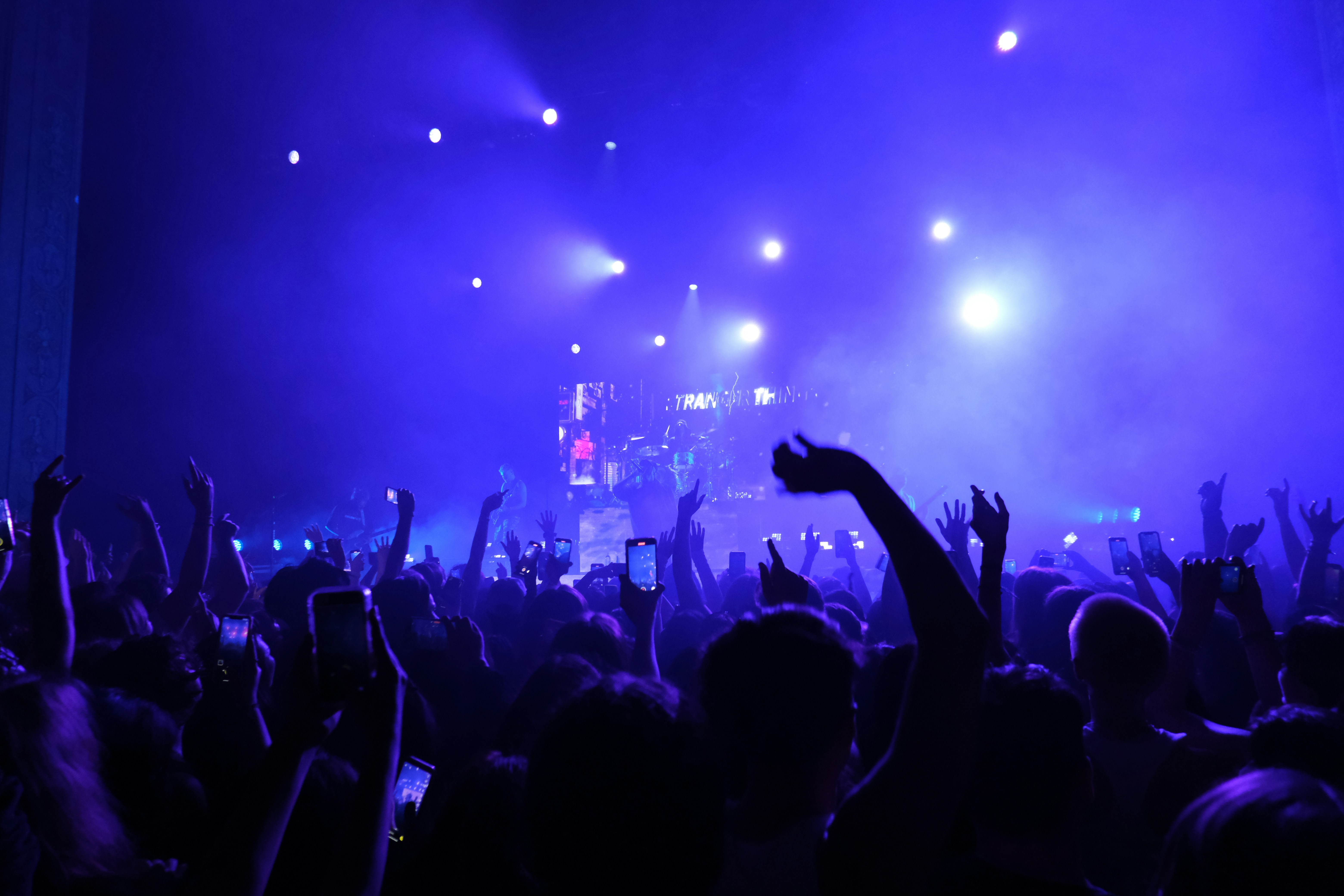 A crowded music concert hall filled with silhouetted audience members