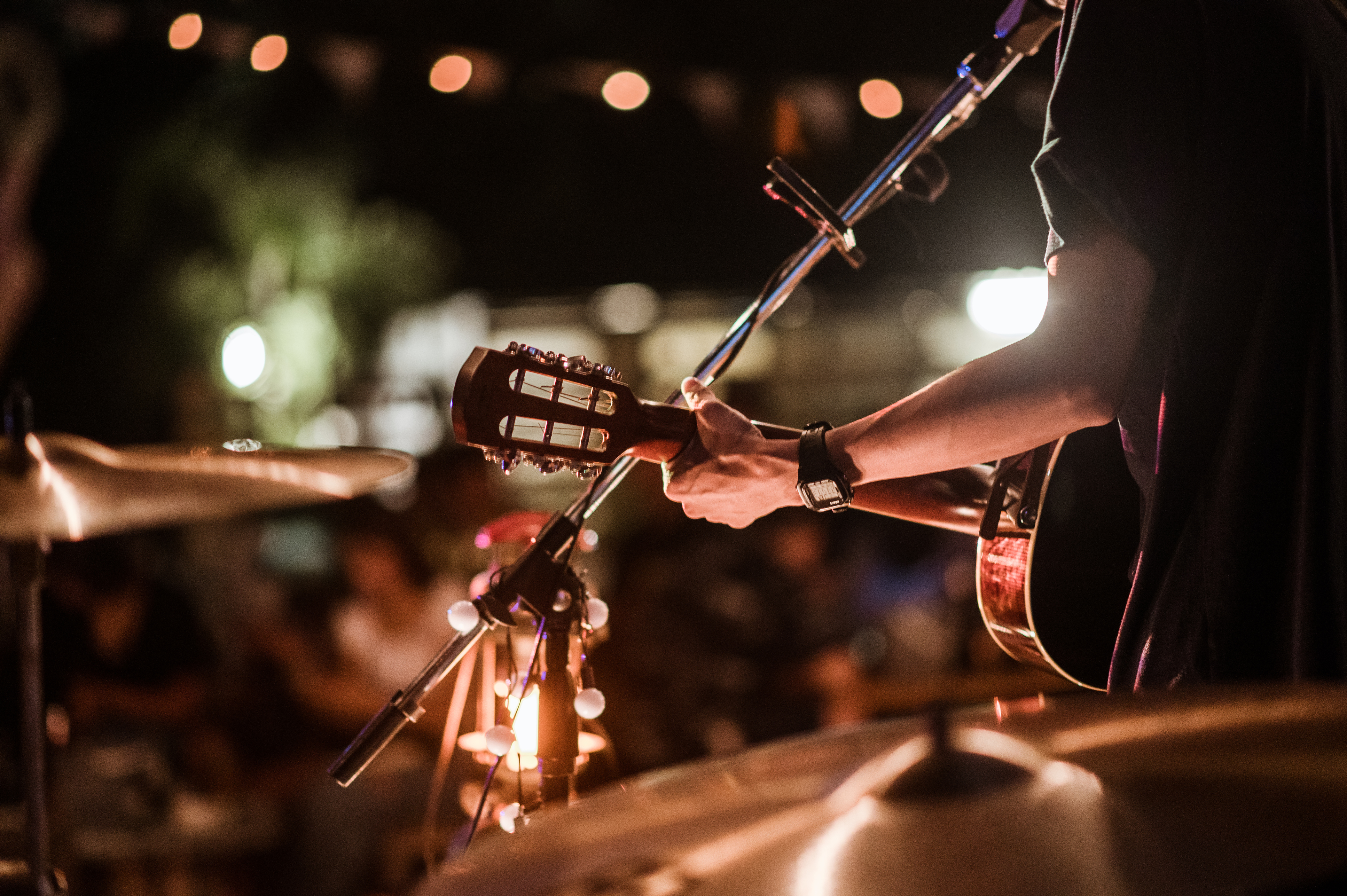 A musician plays an acoustic guitar on a stage with a microphone