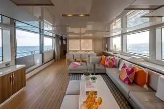 Looking forward in the beach club-style saloon with the sliding glass door and balcony to port