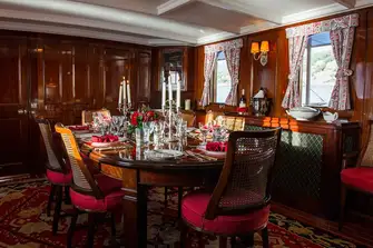 Dine in the mahogany panelled dining room, the beating heart of the yacht